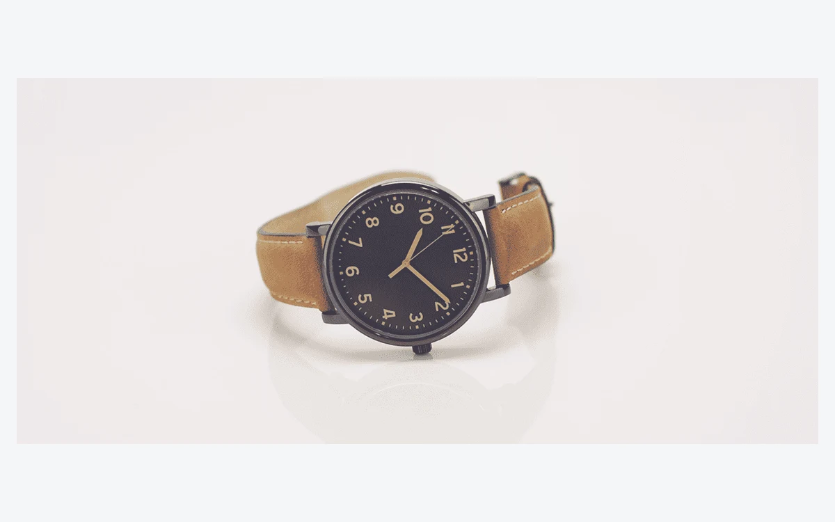 Product photo of a wristwatch with a black dial and tan leather strap on a plain white surface