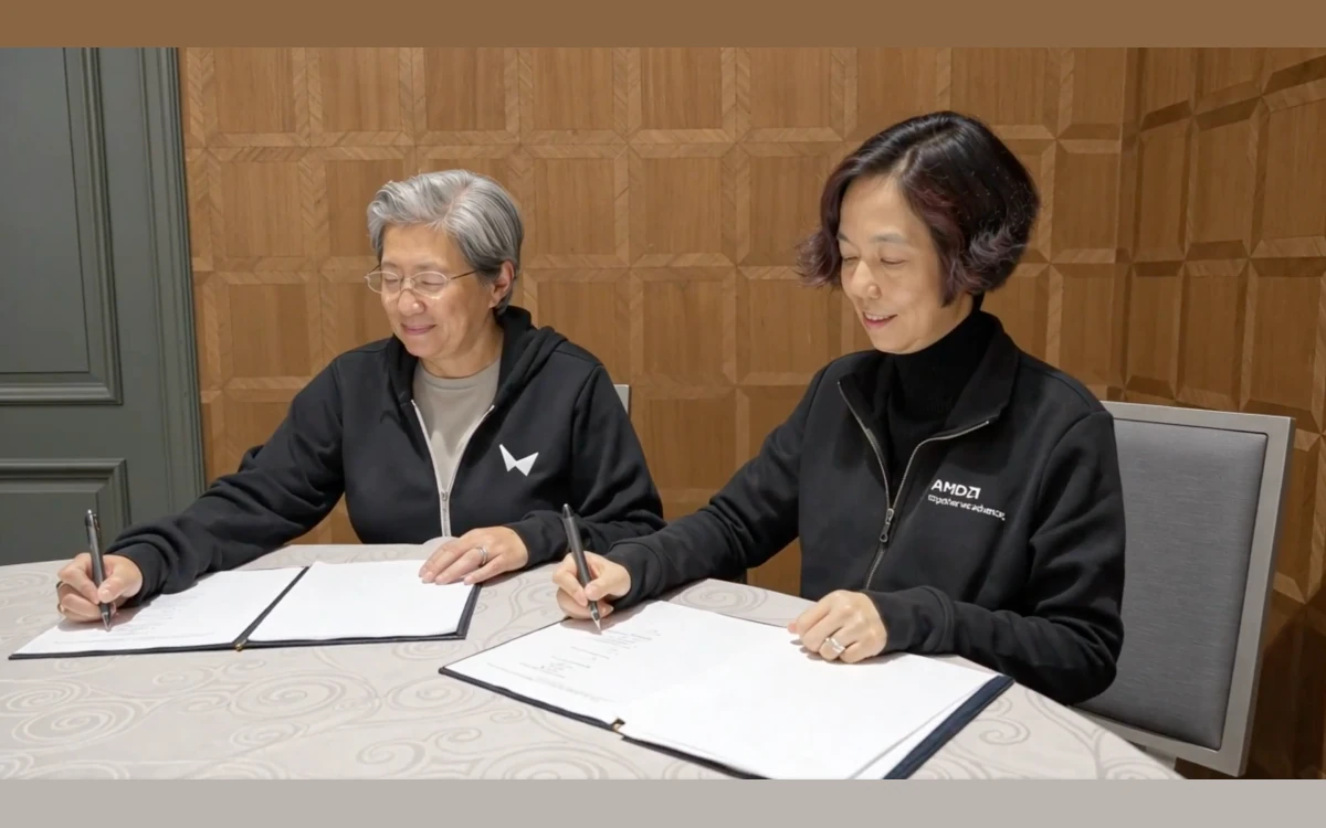 The AMD and World Labs leaders signing documents at a round table, one in a World Labs hoodie and one in an AMD jacket