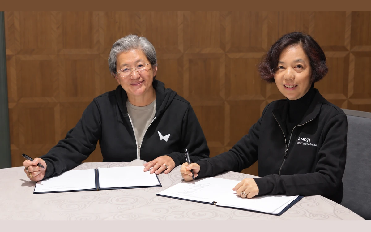 The AMD and World Labs leaders smiling at the camera with pens over open signing folders